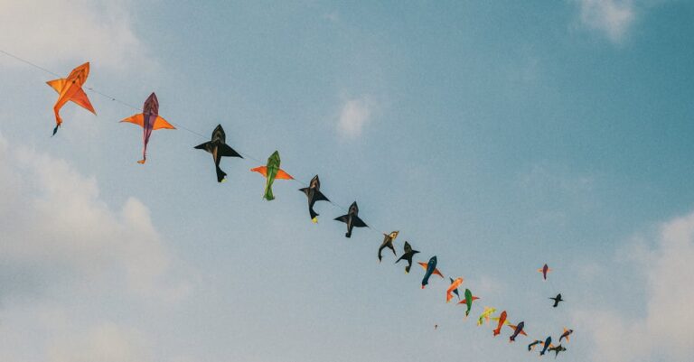 A vibrant array of kites soaring in a clear blue sky, perfect for a sunny day.